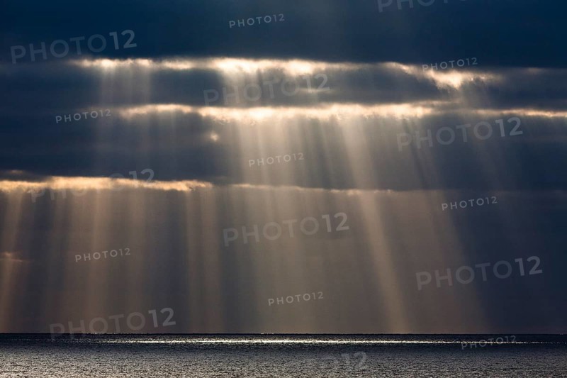 Sun rays shine through dark storm clouds