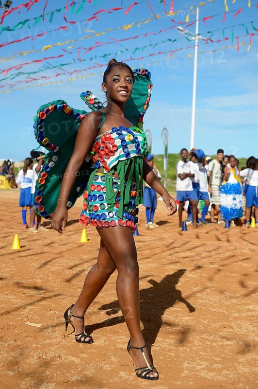 Teenage girl presenting a butterfly costume made of recycled materials such as lids of plastic bottles at a fashion show of a social project
