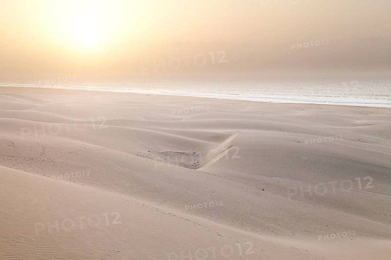 Sun in the mist of the sea above the sand dunes on Praia de Chaves Beach