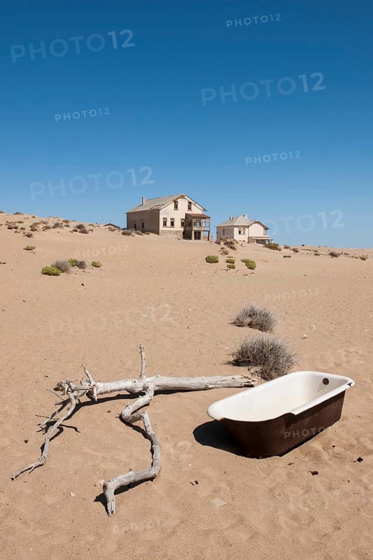 Old bathtub and houses of a former diamond miners settlement that is slowly covered by the sand of the Namib Desert