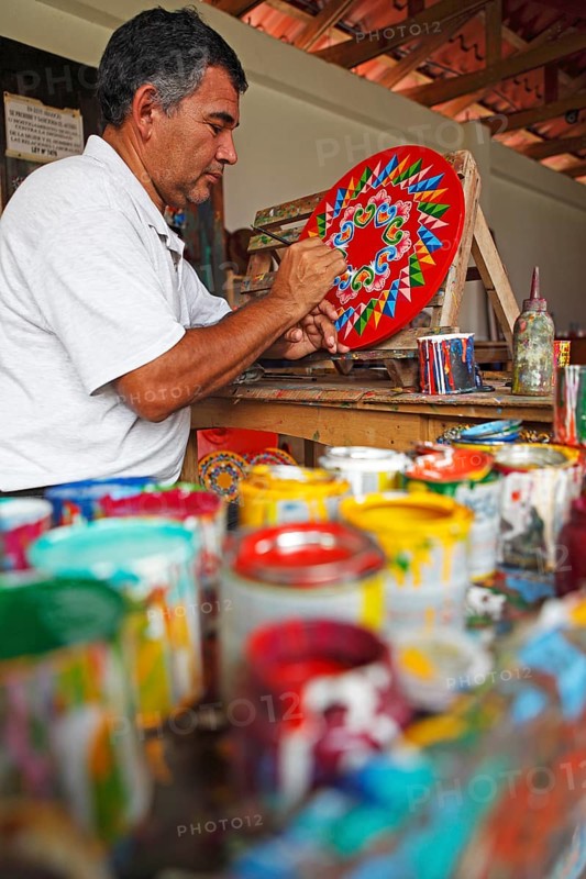 Man painting the hub of a traditional oxcart or Carreta