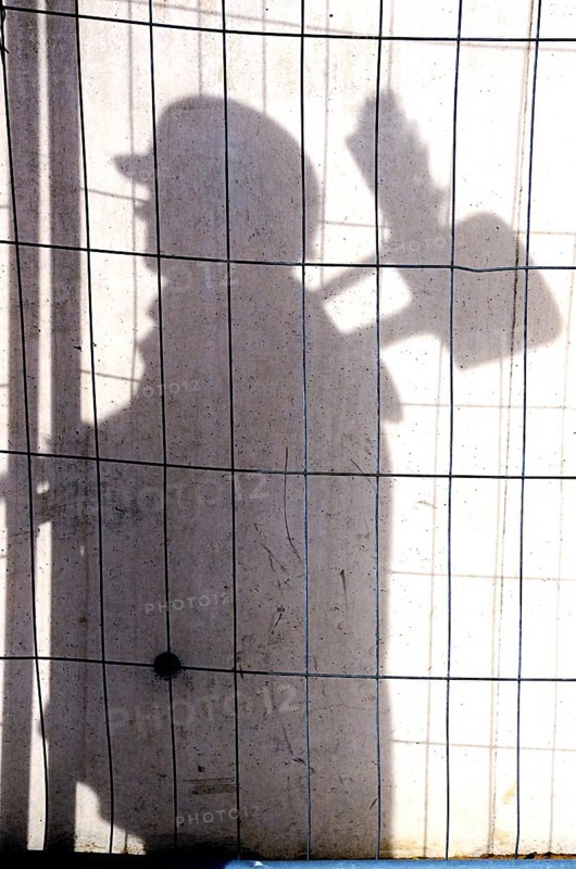 Shadow of a construction worker on a concrete wall