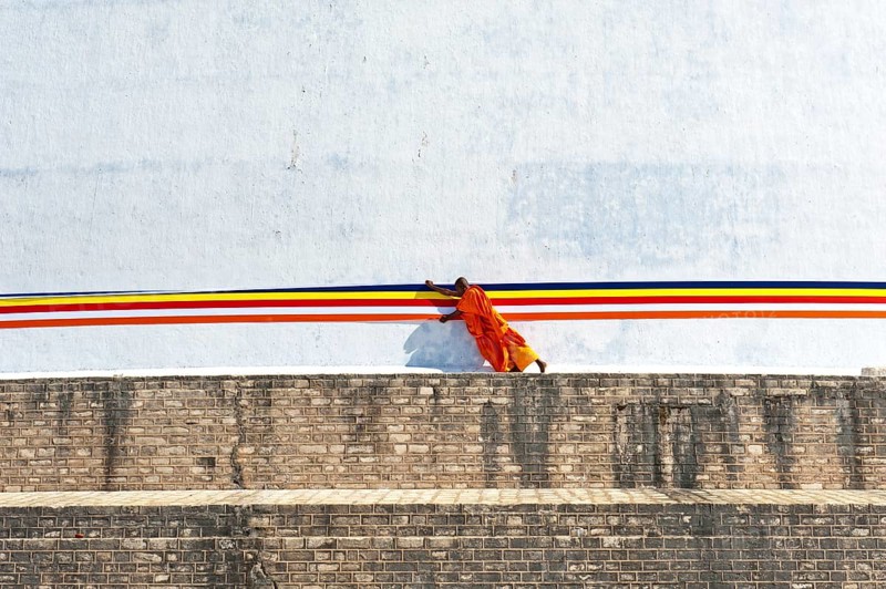 Monk tying a cloth around a large white stupa