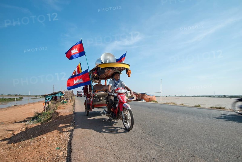 Cambodian monks and novices on a tuktuk with Buddhist flags and national flags of Cambodia at a protest