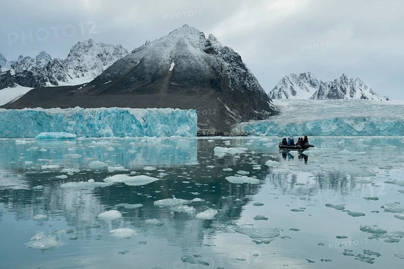 Tourists in a rubber dinghy in front of the rim of the Monacobreen Glacier