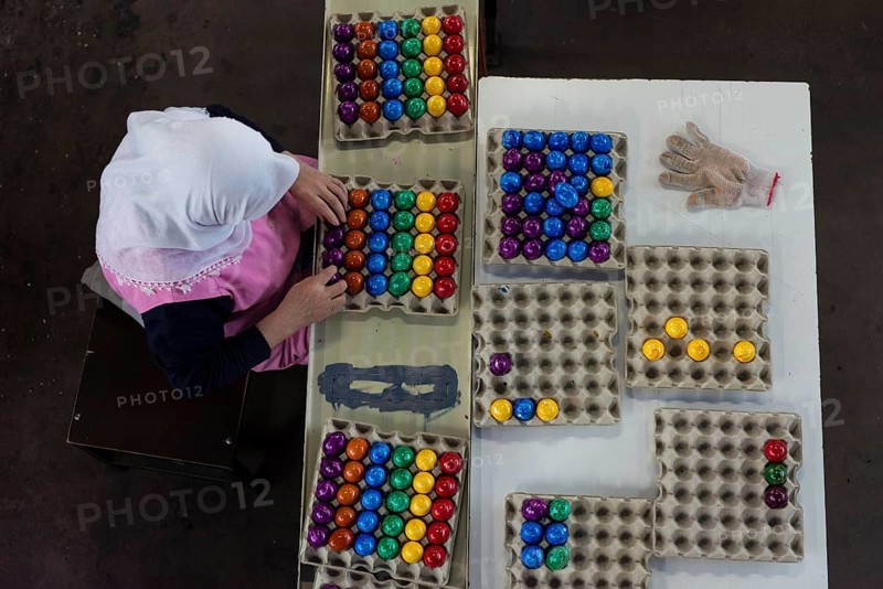 Worker during quality control of colourful dyed Easter eggs