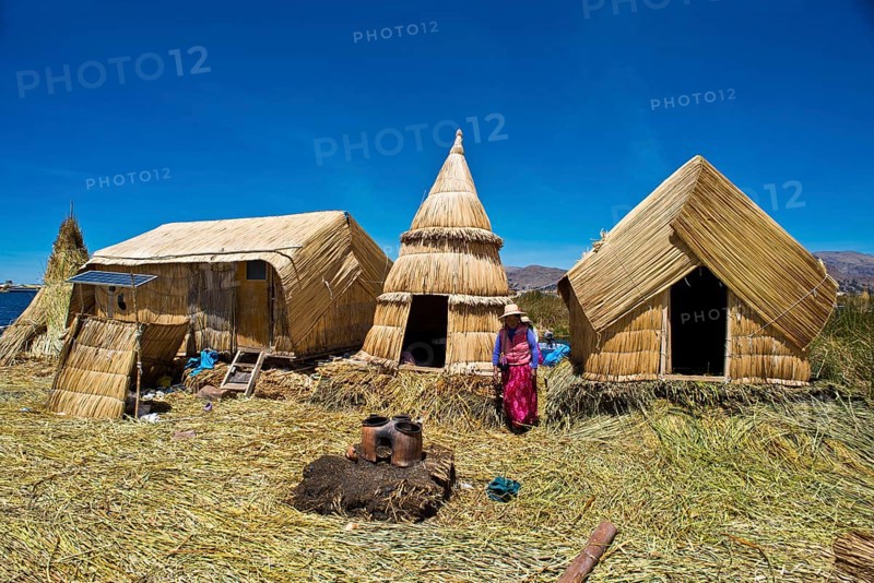 Woman of the Uro Indians in front of typical reed huts
