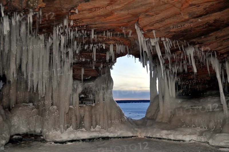 Icicles and ice formations in a cave and view through a natural window onto frozen Lake Superior