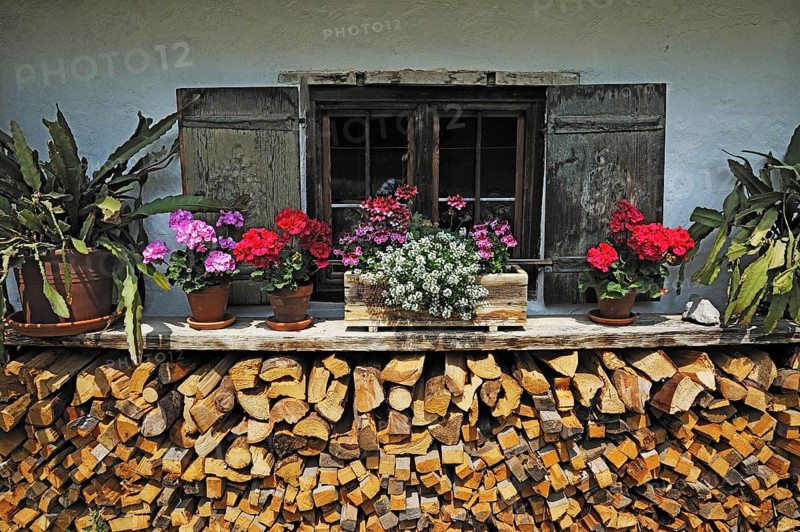 Windows behind a woodpile and flowers in Markus Wasmeier Farm and Winter Sports Museum