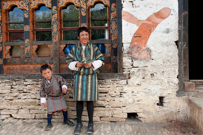 Father and son standing in front of house wall with the mural of a phallus