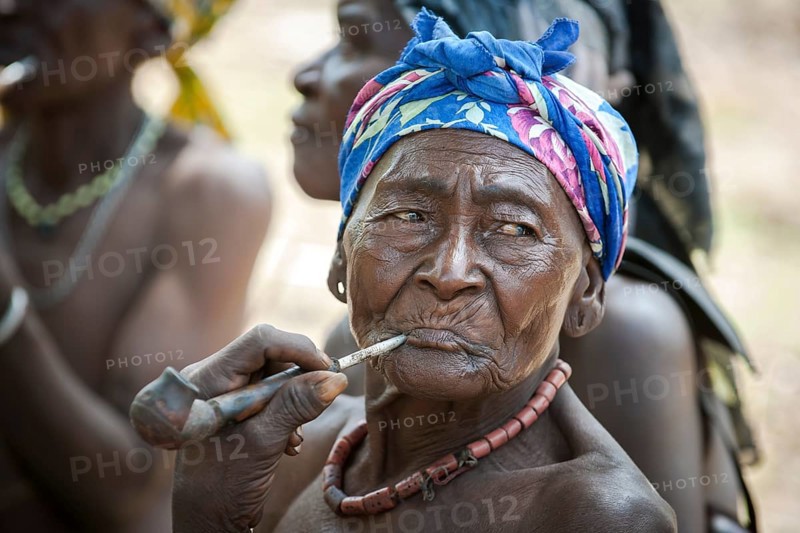 An elderly woman from the Koma people smoking a pipe