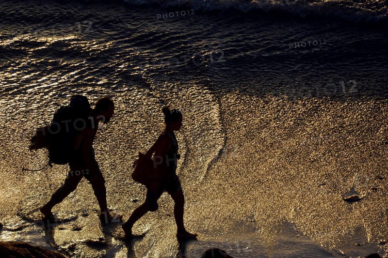 Two backpackers walking along the beach