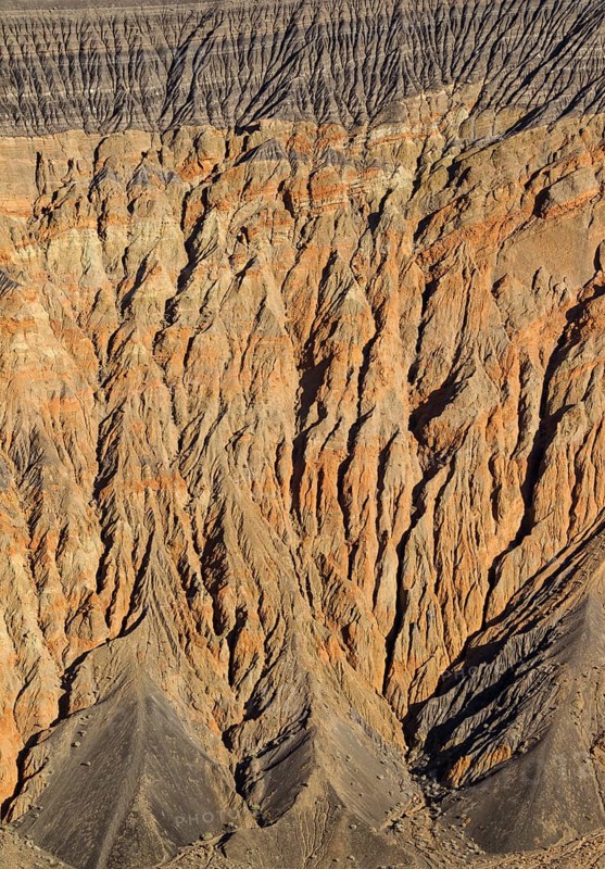 Exposed fissured bedrock of orange-colored conglomerate on the crater wall of Ubehebe Crater
