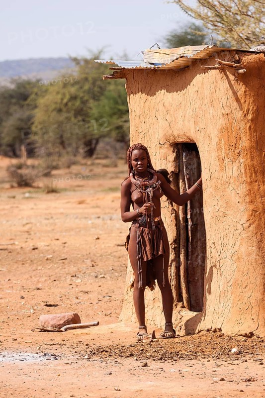 Young Himba in front of her hut