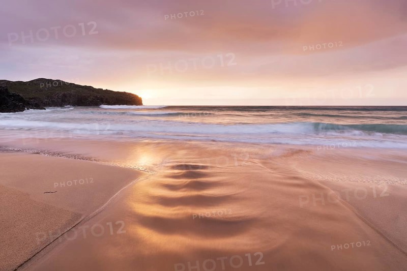 A brook flows over the sandy beach into the sea
