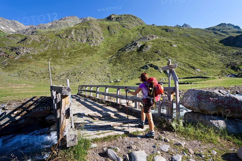 Female mountain climber at Timmelsalm alpine pasture crossing Timmlserbach stream