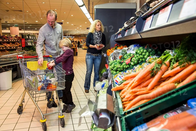 Family shopping with a shopping trolley in the fruit and vegetables department of a supermarket
