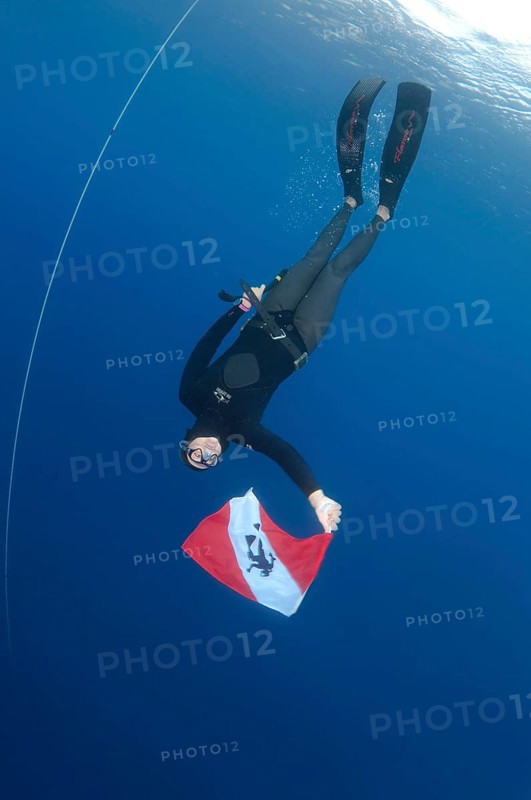 Freediver holds a diver down flag