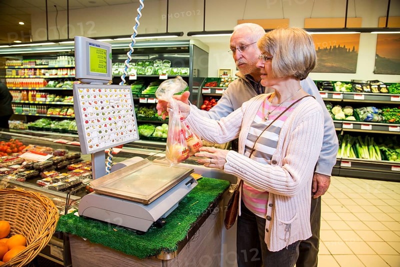 Senior couple weighing fruit at the self-service scales while shopping in the fruit and vegetables department of a supermarket