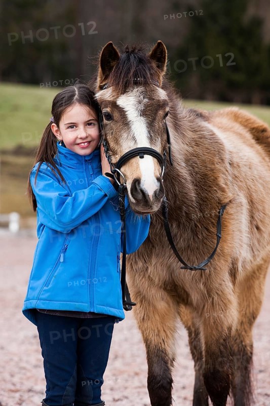 Girl standing beside a pony