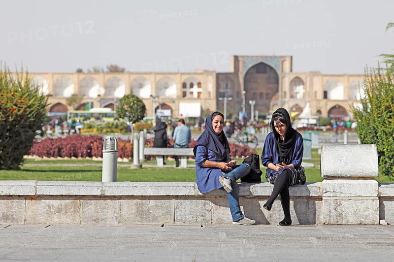Young women using a mobile phone in front of the entrance to the Bazaar