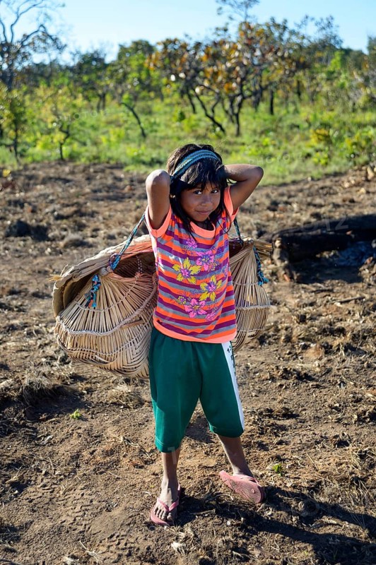 Girl carrying her little sister in a traditional basket on her back