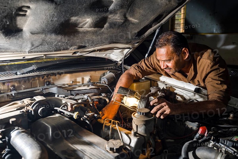 A car mechanic is repairing a BMW car in a garage