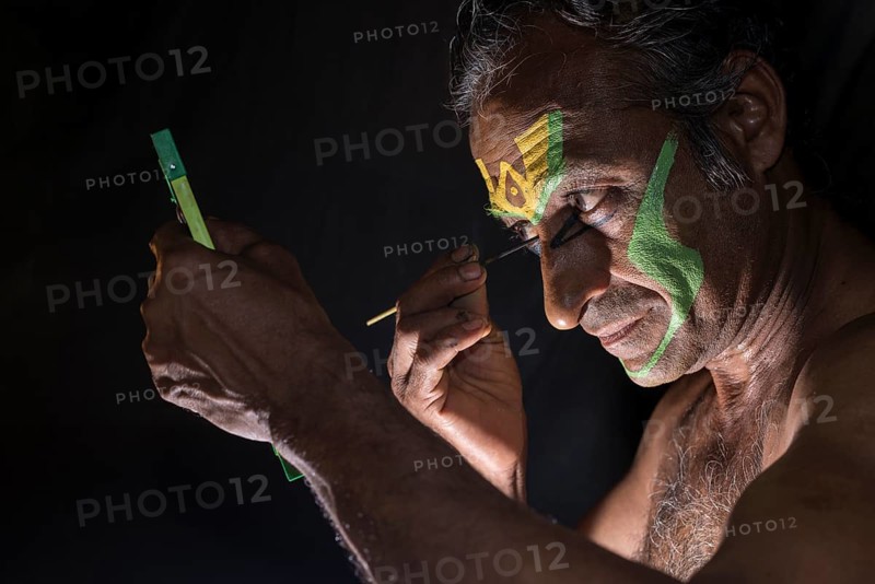 A Katakali artist is applying the make up of the character Arjun for the Kiritam play during a temple festival