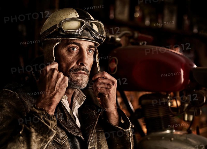 Man with old leather jacket putting on an old motorcycle helmet