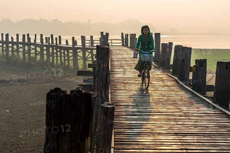 Girl with tanaka on her face riding a bicycle on a teak bridge