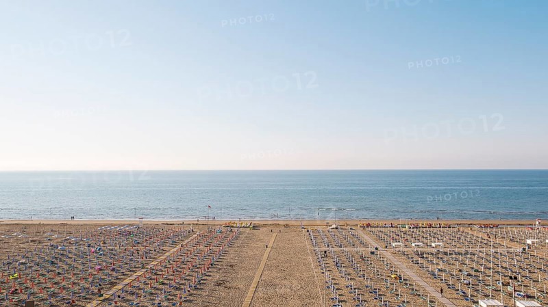 View of a beach with sunshades and sun beds at sunrise