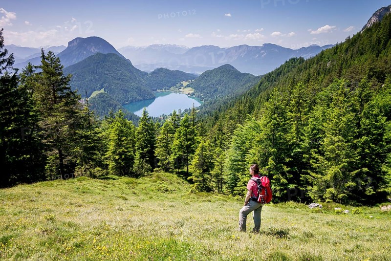 Female hiker observing the view from the Wilder-Kaiser-Steig hiking trail towards Lake Hintersteiner See