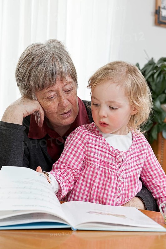 Grandmother reading from a book to her granddaughter