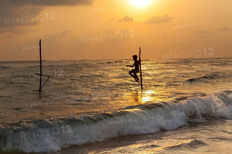 Stilt fisherman fishing in shallow water