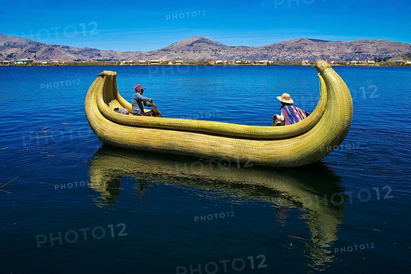Two local people rowing a traditional boat made of totora reeds on Lake Titicaca