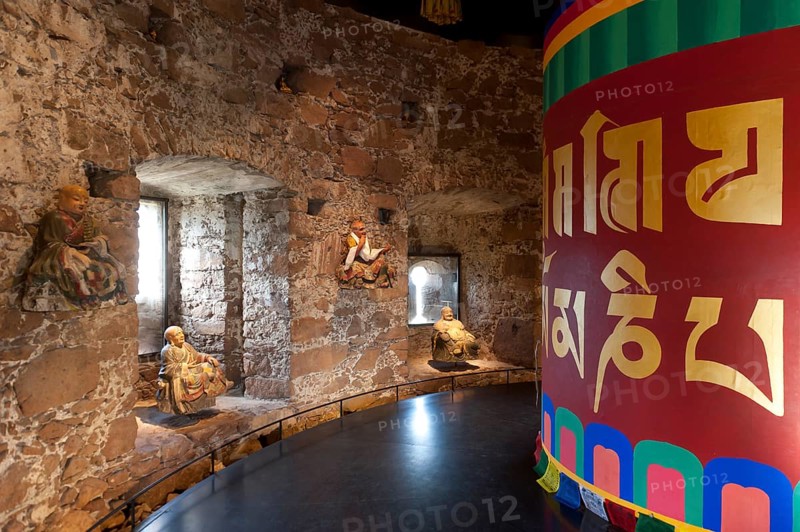 Room with a Tibetan prayer wheel and Buddha statues
