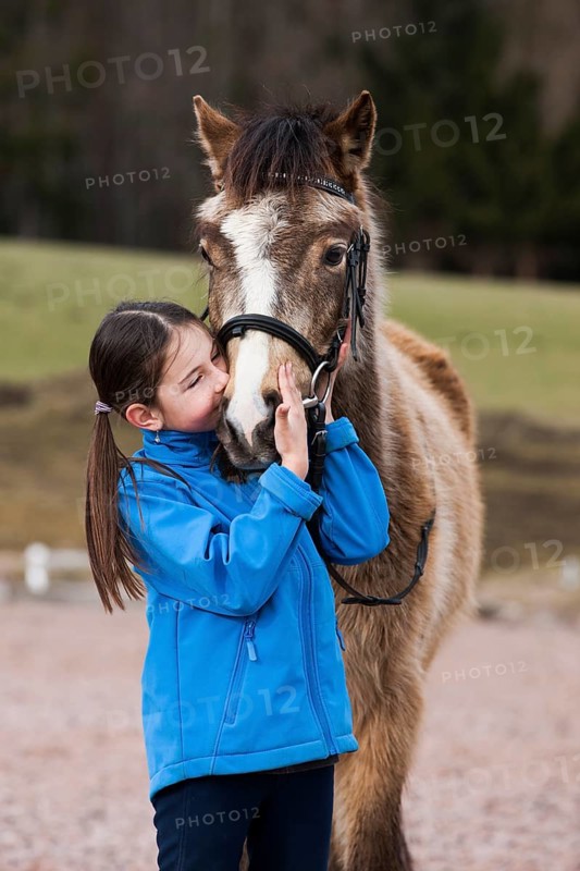 Girl cuddling with a pony