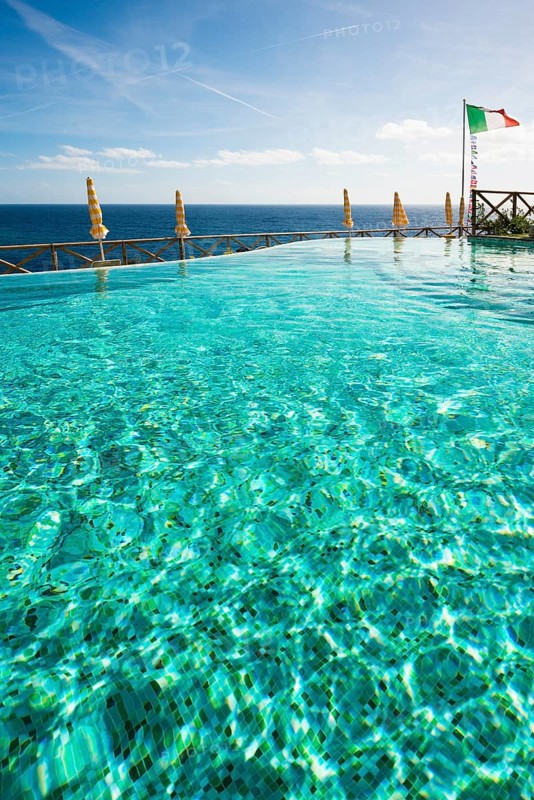 Swimming pool and the Mediterranean with the flag of Italy