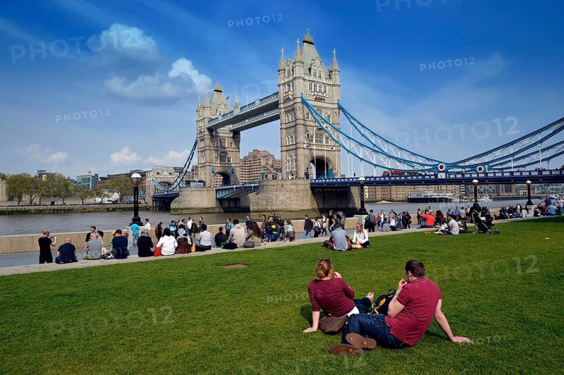 Tourists relaxing in Potters Fields Park in front of Tower Bridge