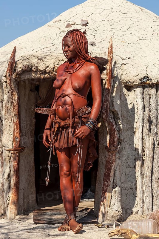 Young Himba woman standing in front of her hut