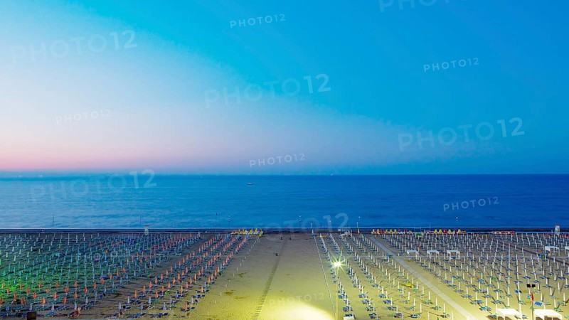 View of a beach with sunshades and sun beds at twilight