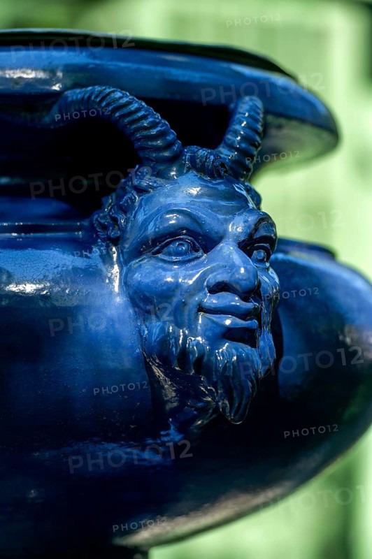 Human-animal head on an ornamental vessel made of glazed ceramic