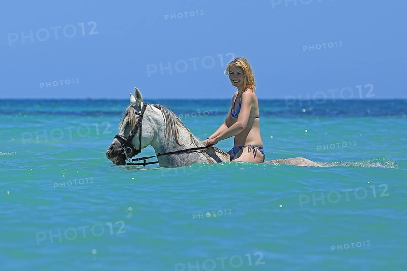 Woman wearing a bikini riding a Barb horse in the sea