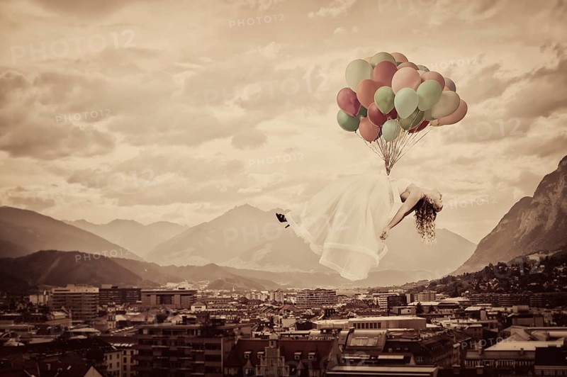 Bride floating on balloons over Innsbruck