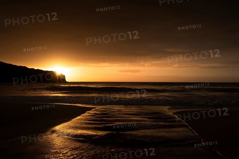 A brook flows over the sandy beach into the sea