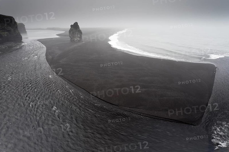 Black lava beach with a basalt rock