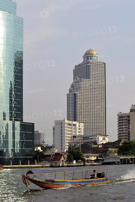 Long-tail boat on the Chao Phraya River with the State Tower at back