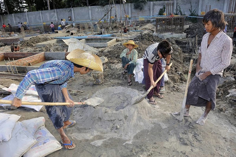 Children and teenagers mix concrete on a high rise construction site
