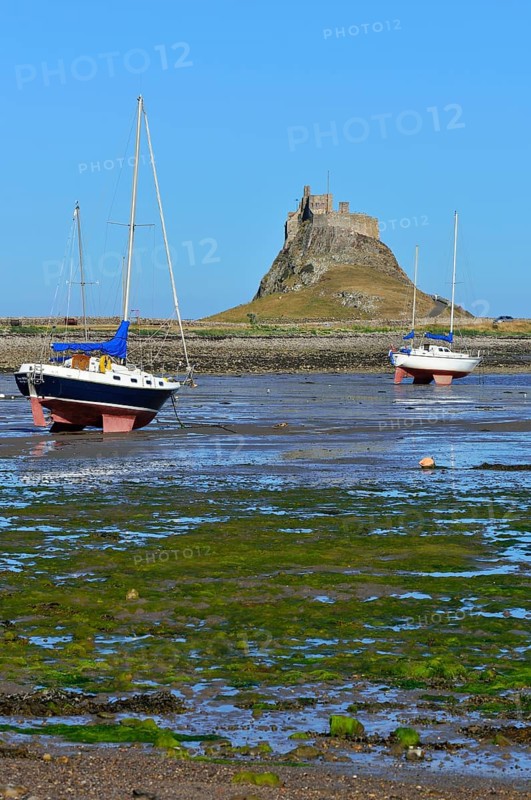 Sailing boats at low tide in the bay off Lindisfarne Castle