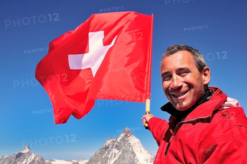 Tourist holding a Swiss flag over the Matterhorn